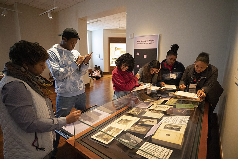 Students interact with an exhibit on women's suffrage