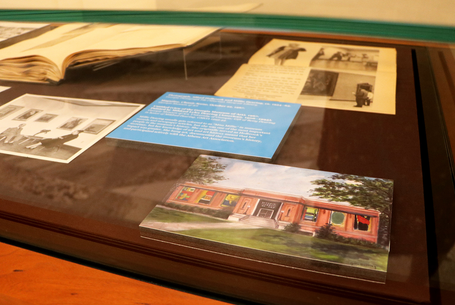 A photograph, a drawing, and a magazine article in a display case