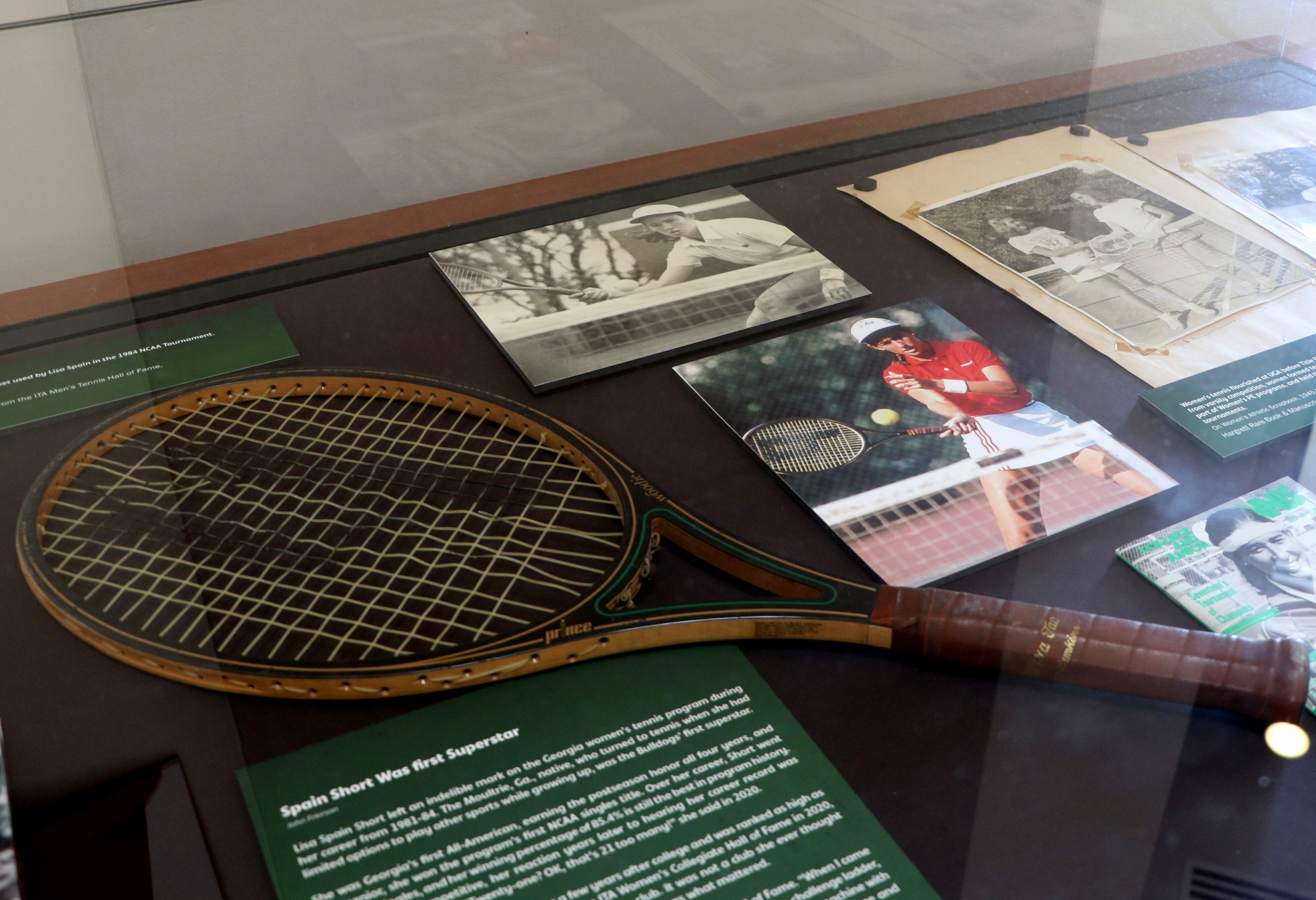 Exhibit case with old tennis racket and historic photos of UGA tennis team