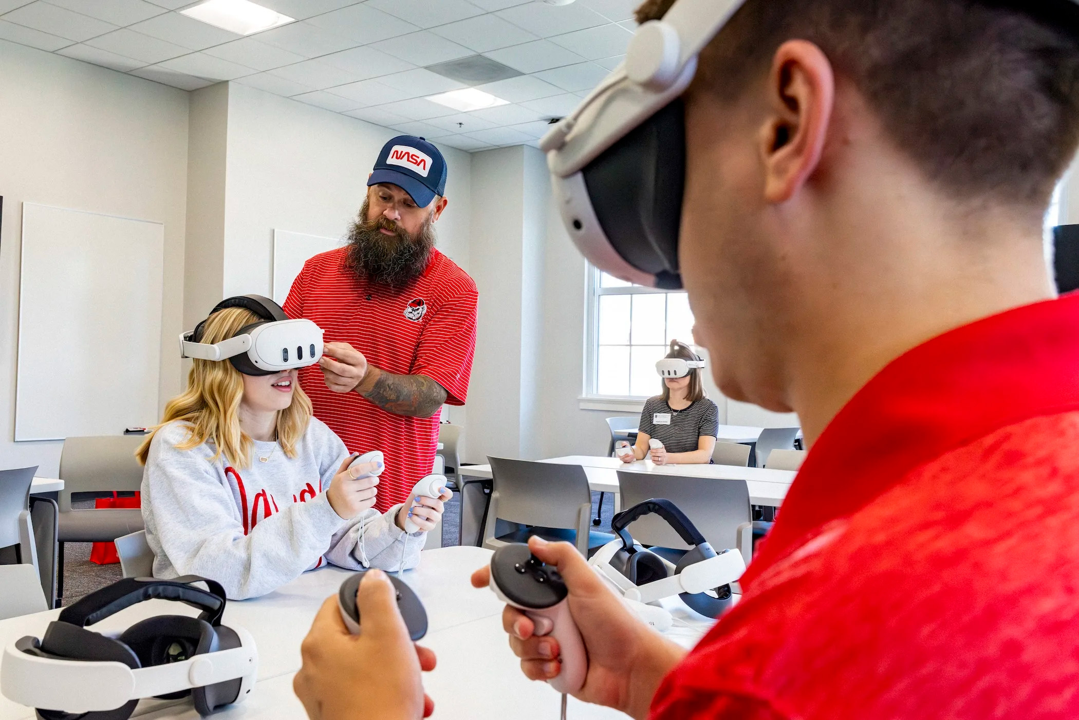 Man adjusts a VR headset on a student's head