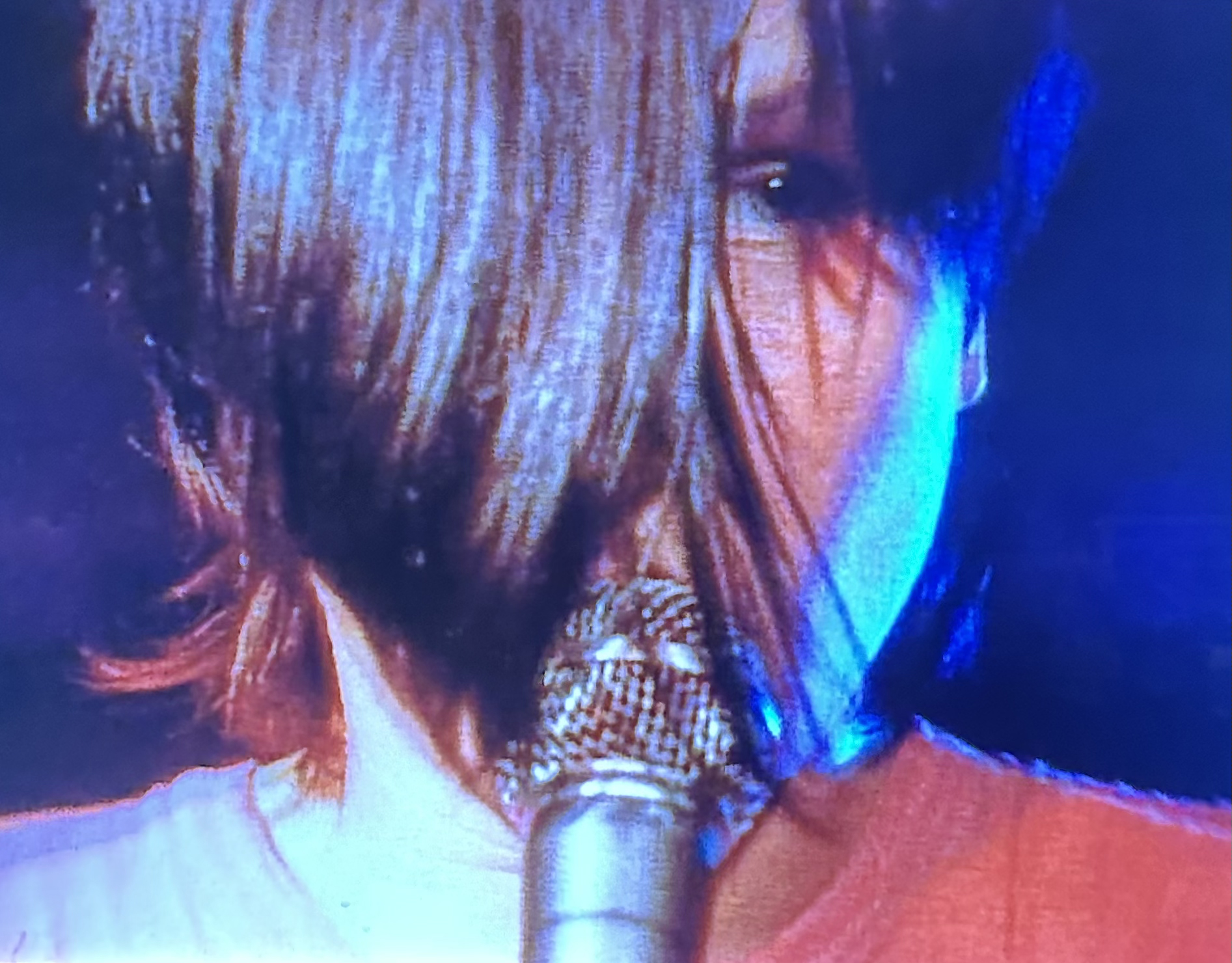 woman with hair covering face sings into a microphone