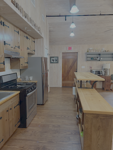 A galley kitchen with wood cabinets and counters and stainless steel appliances.