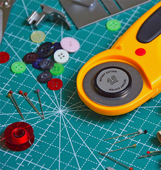 grid board with an assortment of cutting, button, sewing thread and needles