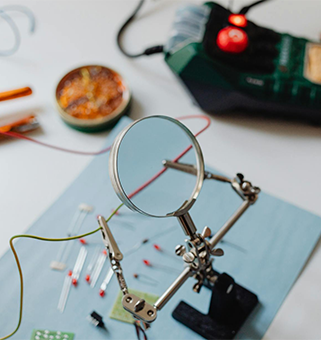 close up photo of a magnifying glass over a spread of soldering project materials