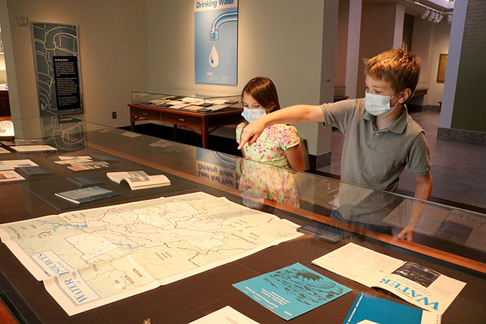 Two children look at items in an exhibit case
