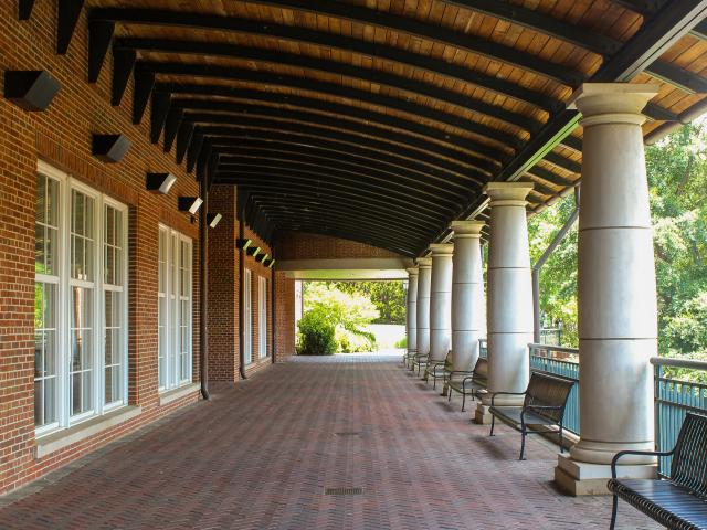 Empty Colonnade with wide brick walkway lined with columns and benches