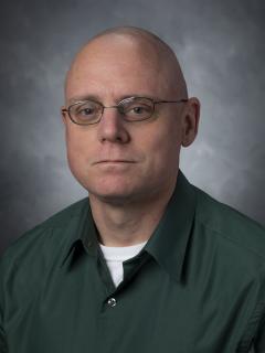Man wearing glasses and a green button down shirt.