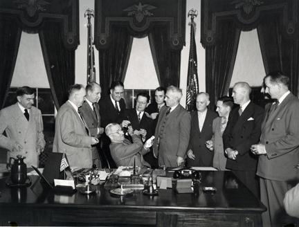 President Harry Truman (seated) signs the National School Lunch Act of 1946.